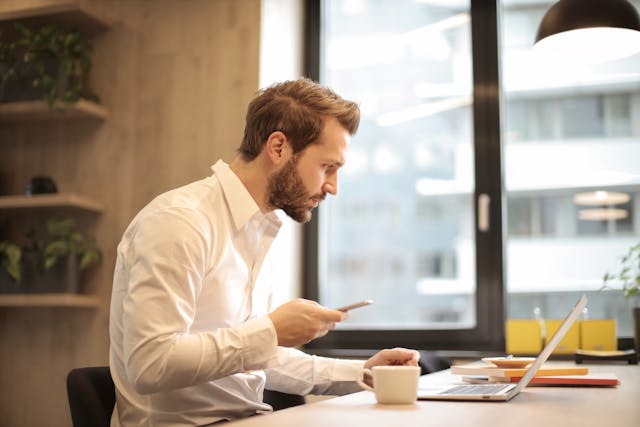 property manager holding their phone while looking at a computer