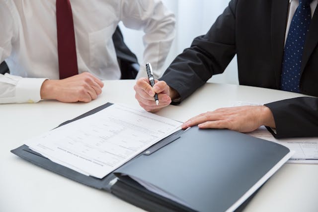 two people sitting in front of a contract ready to sign it