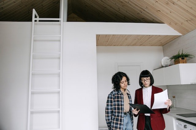 landlord in a red jacket speaking with a tenant in their rented apartment
