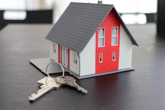 a red house figurine with keys next to it